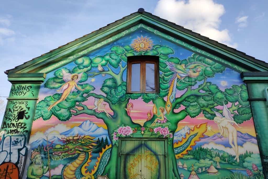 Colourful street art with fairies and a dragon on a gable end at the entrance to Christiania in Copenhagen. One of many free things to see and do in Copenhagen.
