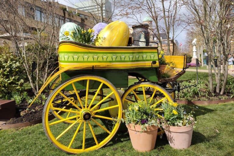 A wooden, bright yellow wagon large, colourful easter eggs inside.